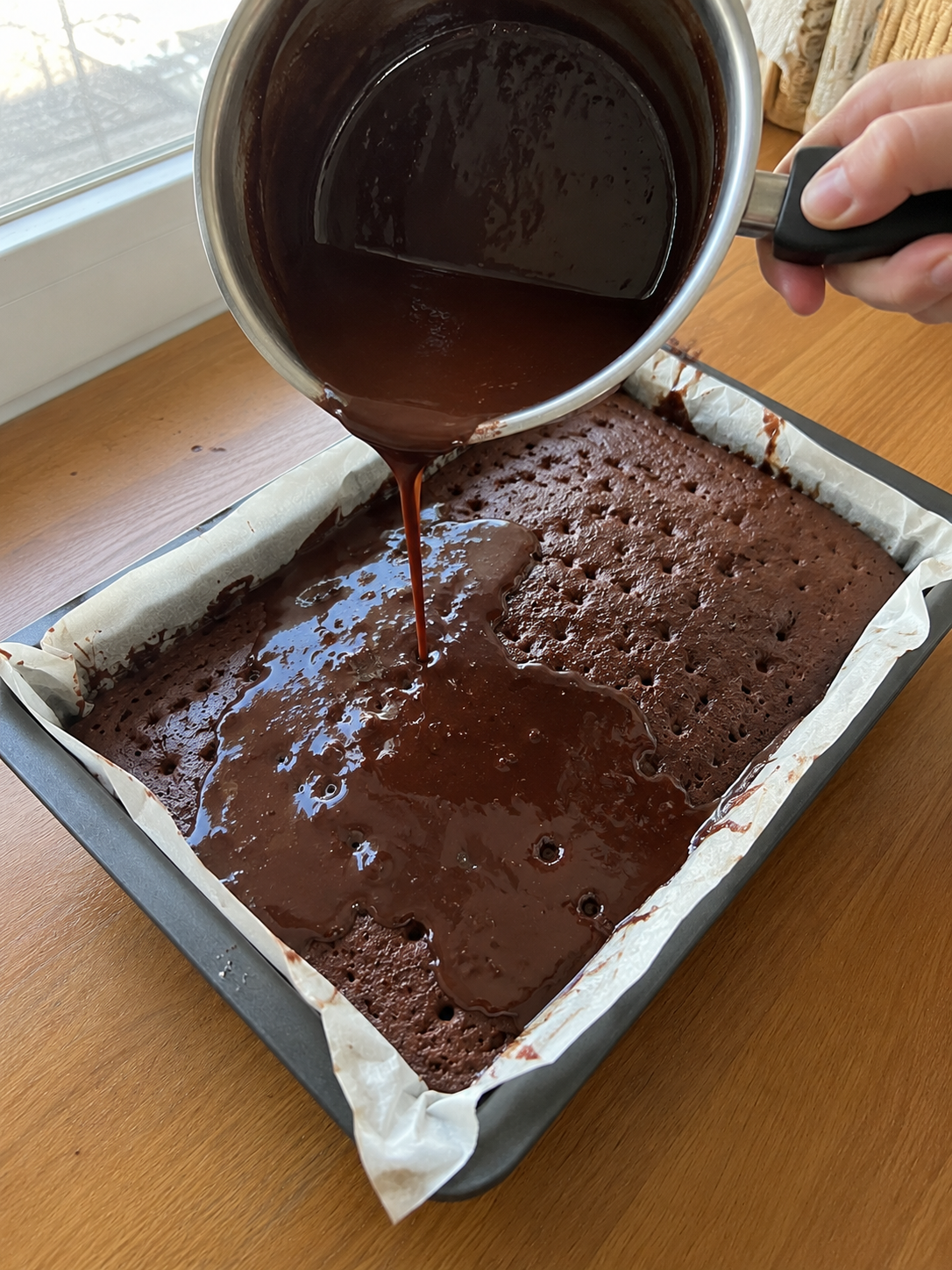 Pouring chocolate cream over cake