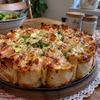 Golden baked tortilla pizza roll-ups in a round dish with a bowl of creamy garlic herb dip