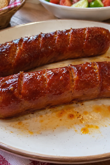 Golden pan-seared smoked sausages in a skillet served with sauerkraut and potatoes