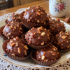 Homemade hazelnut chocolates covered in chopped hazelnuts, one cut open to show the whole hazelnut center