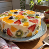 Sliced no-bake yogurt pudding cake with colorful fresh fruit pieces on a white plate