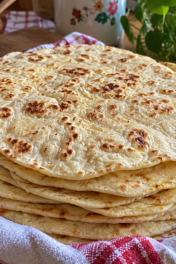 Stack of soft homemade flour tortillas in a cloth with golden spots
